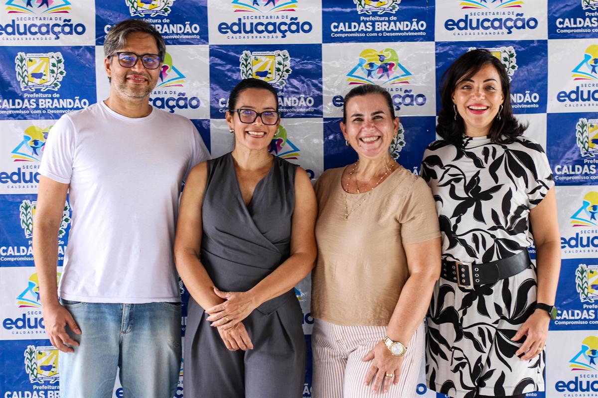 Equipe reunida diante do painel da Secretaria de Educação de Caldas Brandão
